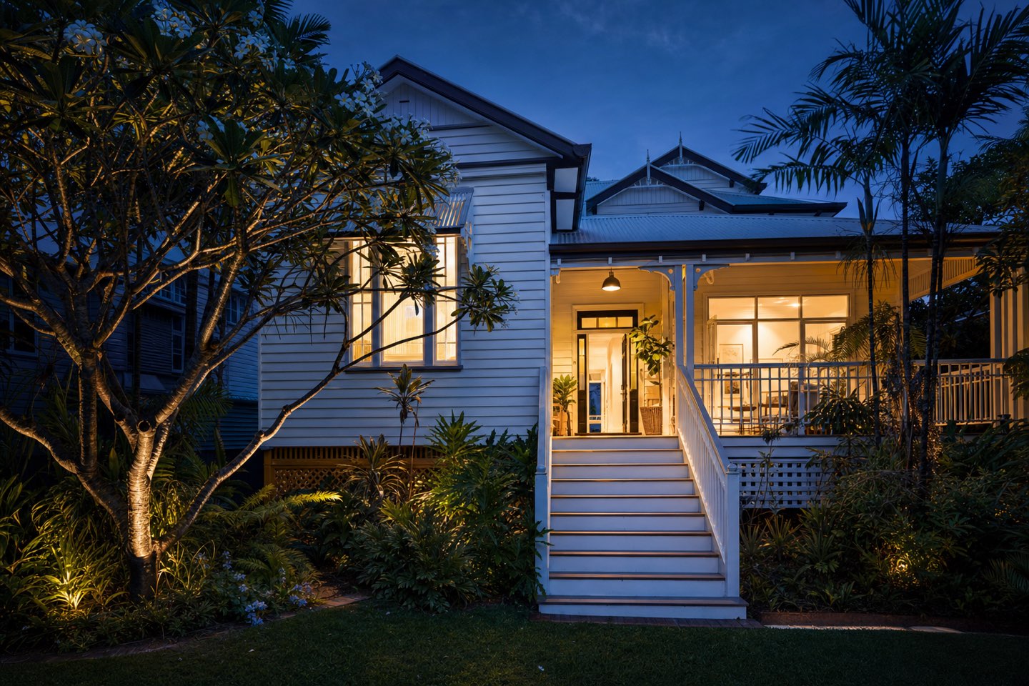 A renovated Queenslander home in Brisbane glowing at dusk