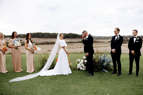 A bridal party on a lawn at golden hour